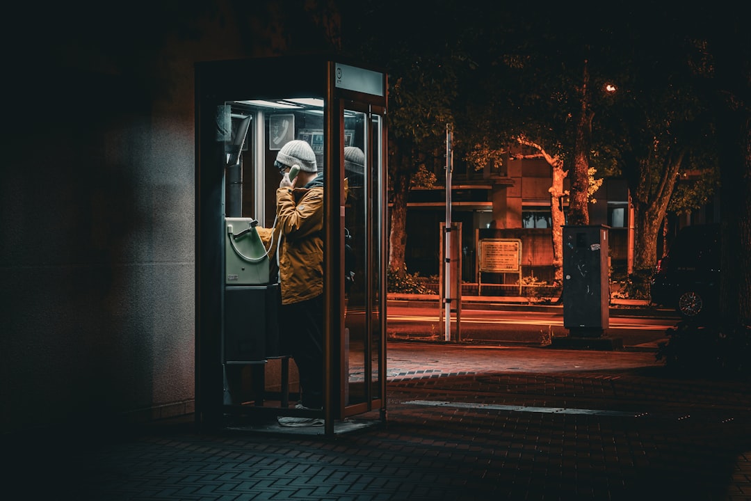 Person using a payphone at night