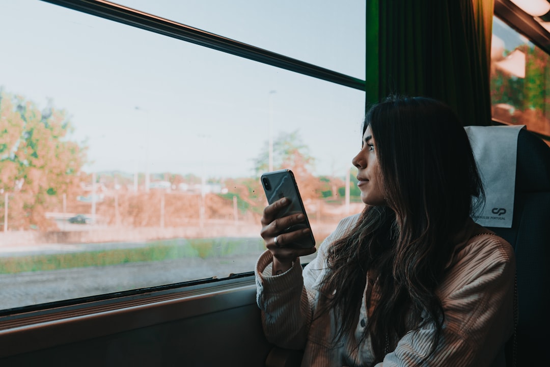 Woman in a white and gray jacket holding a black smartphone