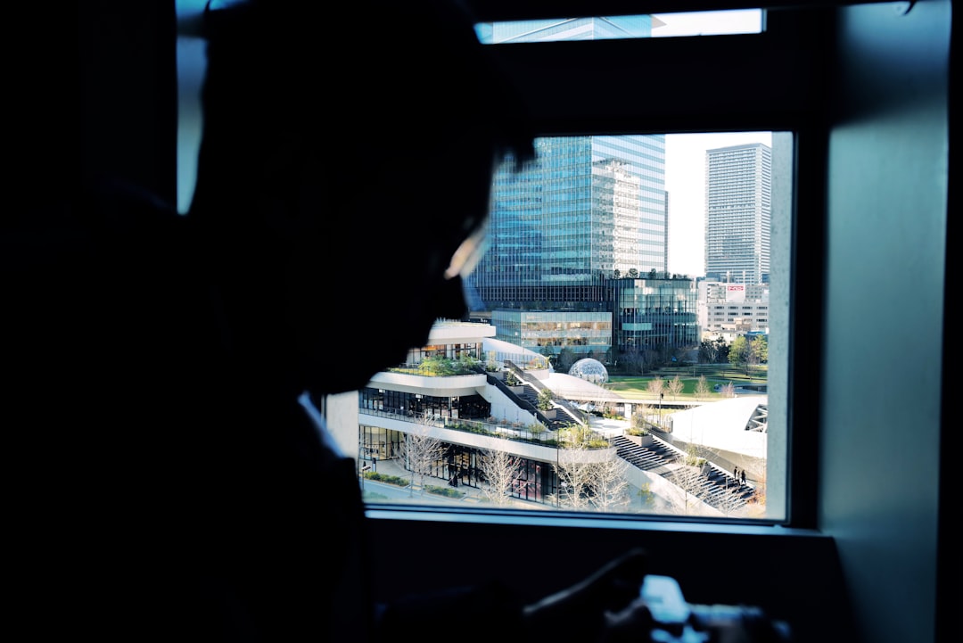 Silhouette of person looking out window at cityscape