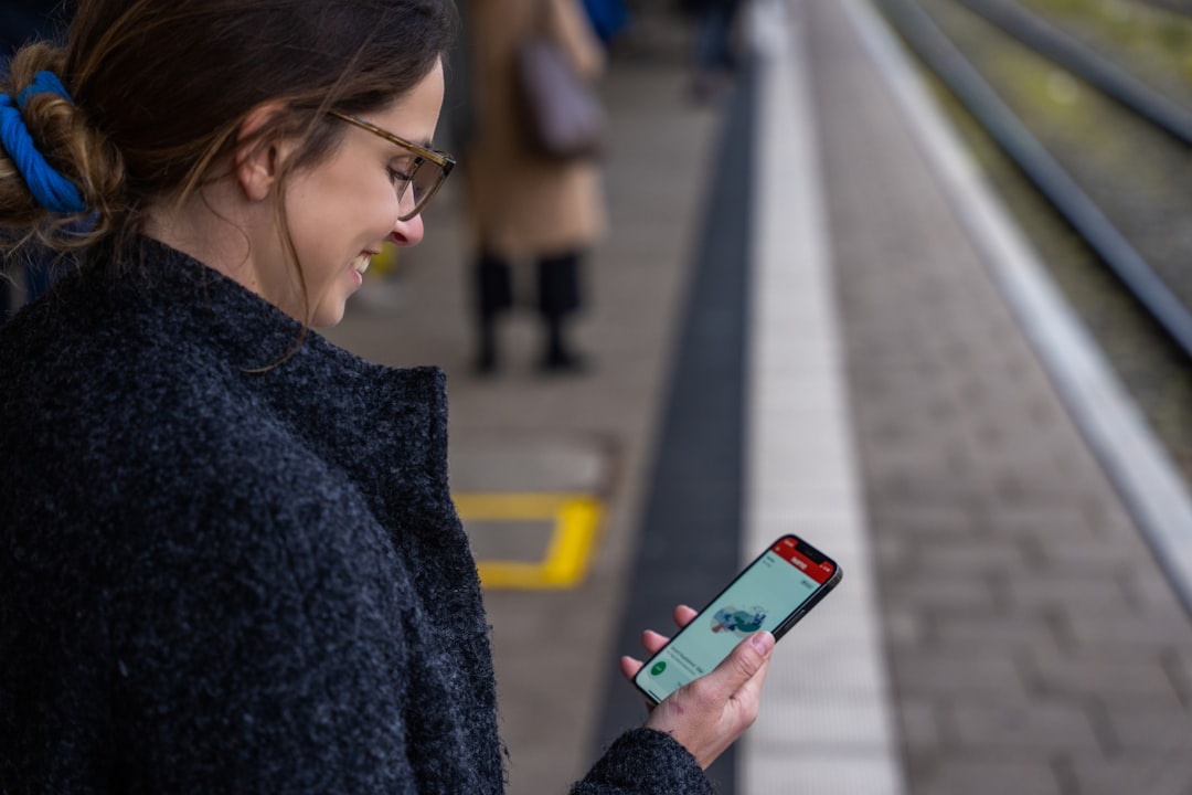 A woman standing on a train platform looking at her phone