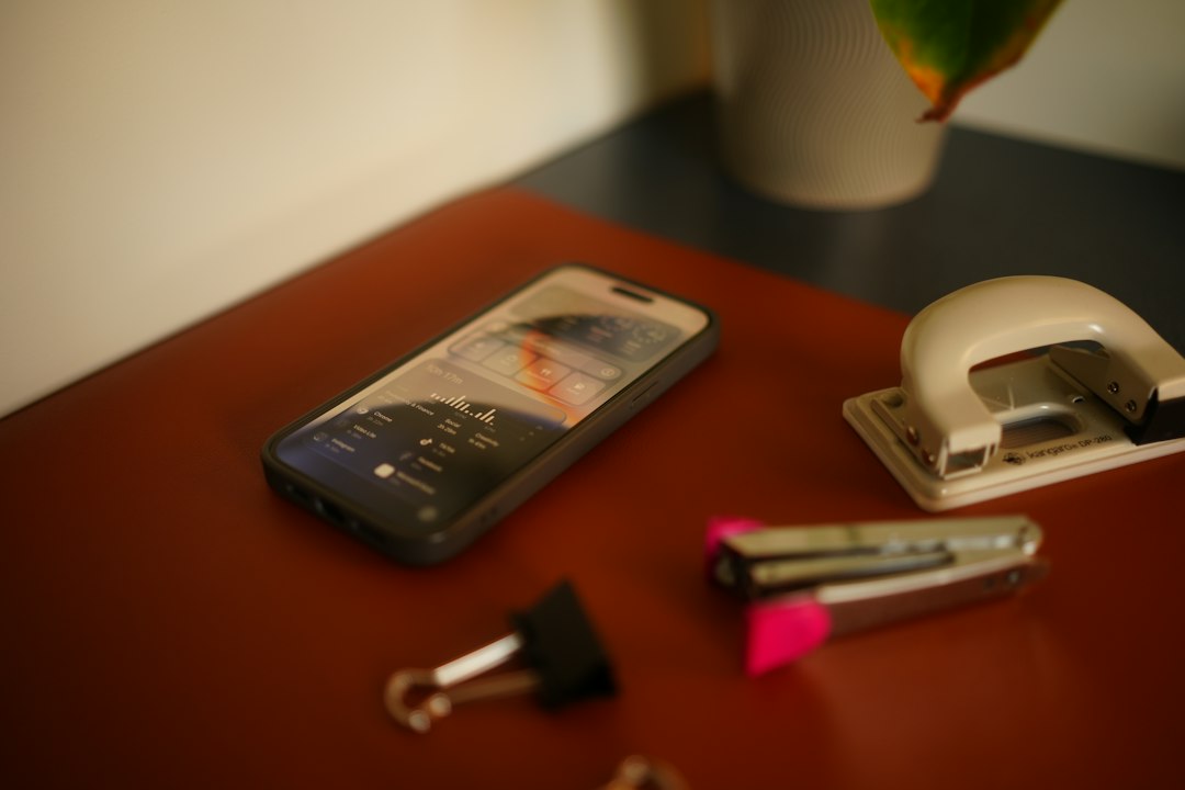 A smartphone displaying screen time statistics on a brown desk with office supplies