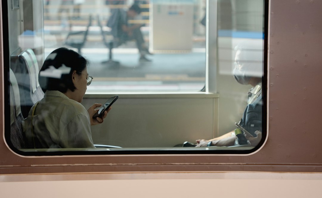 A man sitting on a train looking at his cell phone
