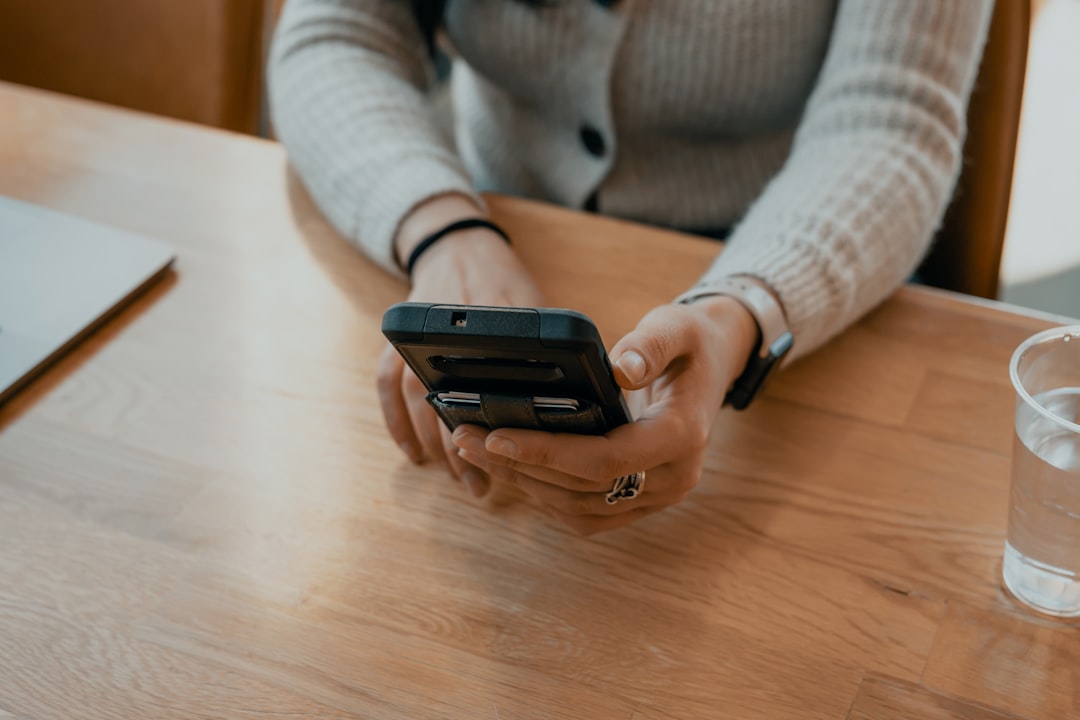 mujer con suéter blanco sosteniendo un smartphone negro