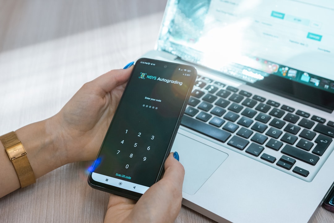 una persona sosteniendo un teléfono móvil frente a una laptop