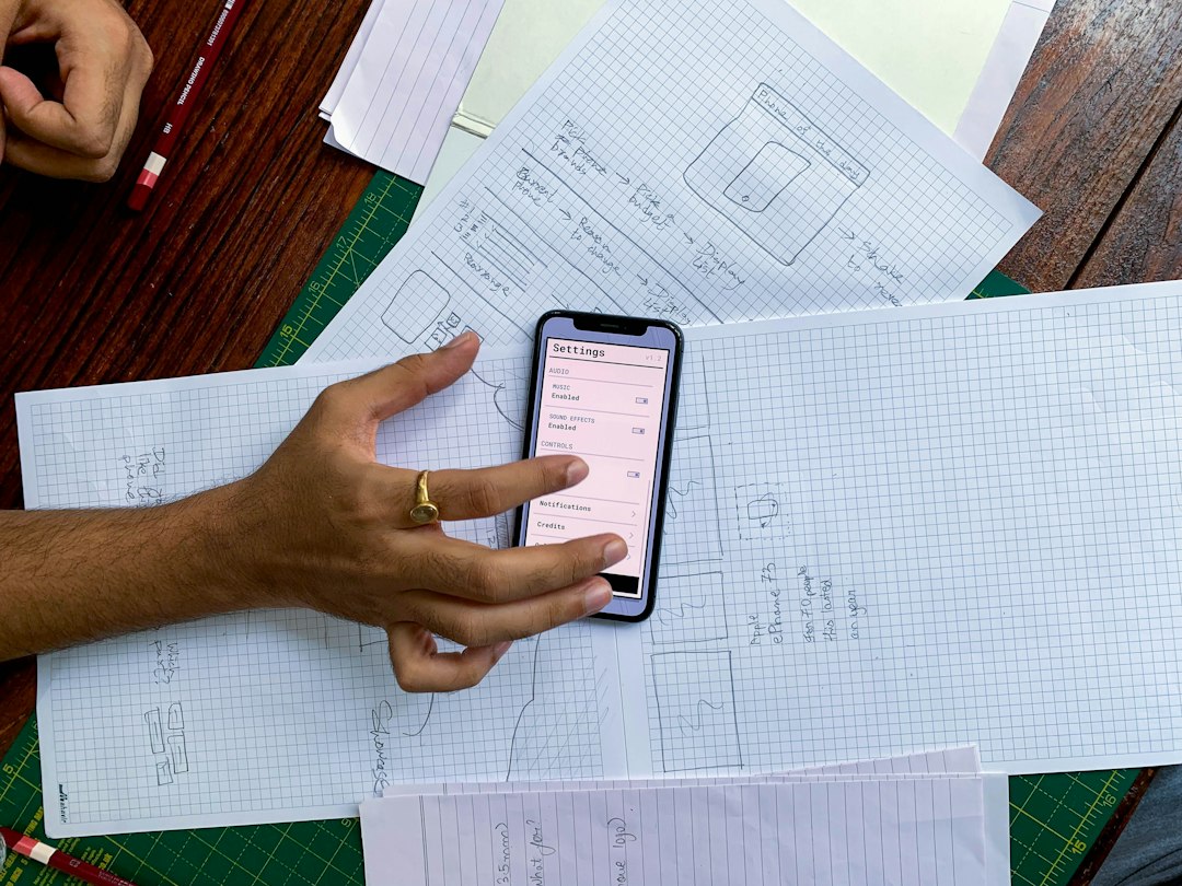 una persona sosteniendo un teléfono celular sobre una mesa
