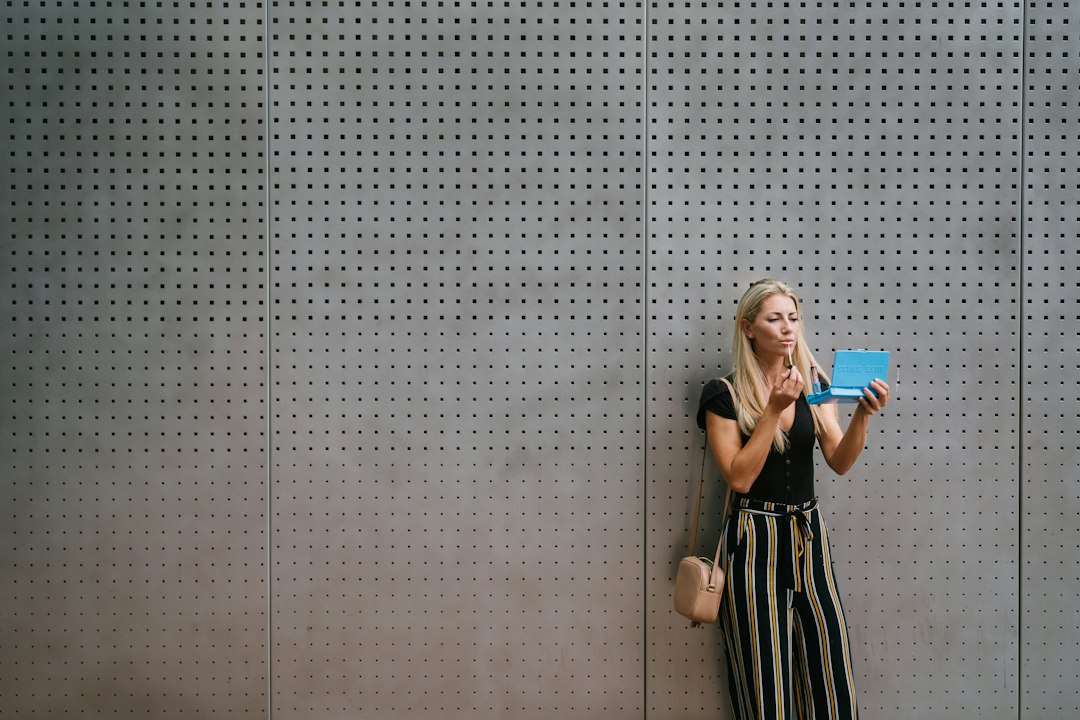 woman in black and white stripe dress standing beside gray wall